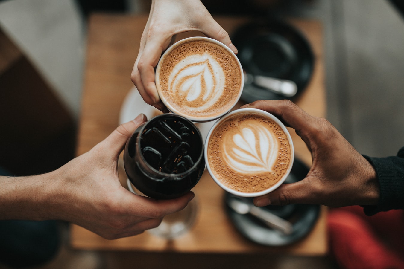 Three people toasting with cups of coffee